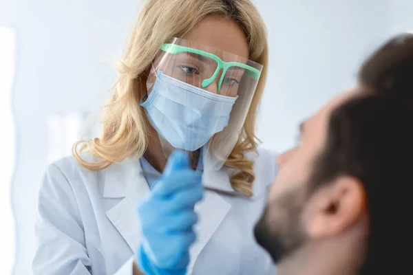 Female dentist in face mask and protective glasses making treatment — Fotografia de Stock