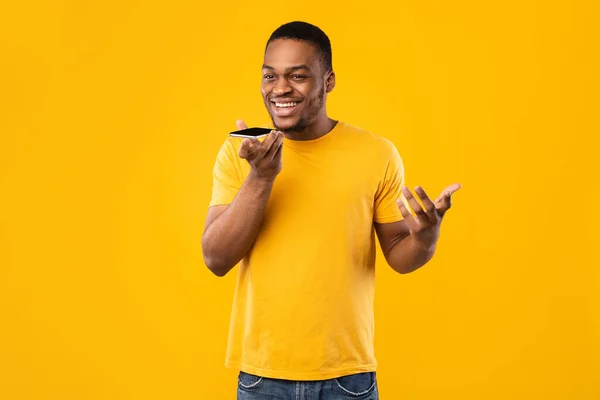 Black Guy Talking On Phone With Loudspeaker Mode, Yellow Background — Stockfoto