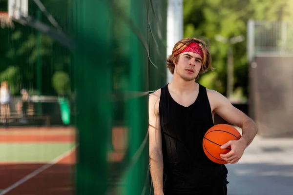 Handsome millennial player in sportswear ready to play ball at outdoor basketball court, empty space — Stok Foto