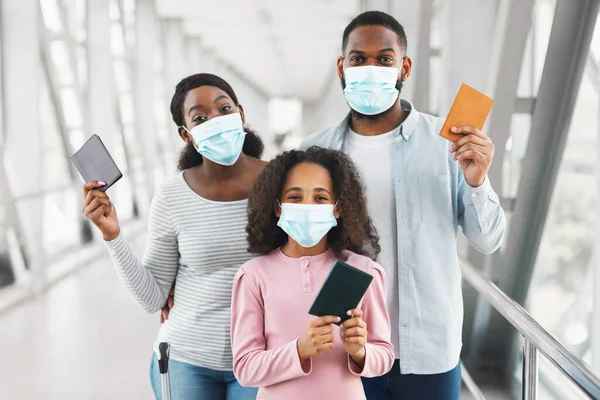 Black family in masks traveling, holding documents in airport —  Fotos de Stock
