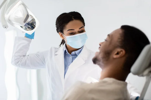 Концепція стоматології. Молодий чорний пацієнт оглянути з стоматолог жінка — стокове фото