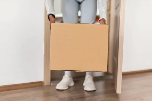 Unrecognizable African American Lady Taking Delivered Box From Floor Indoor — стоковое фото