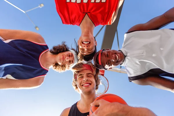 Group of happy basketball players putting their heads together in unity outdoors, bottom view — Stok Foto