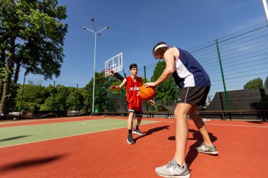 Millennial basketball players practicing their moves together at outdoor sports stadium, copy space