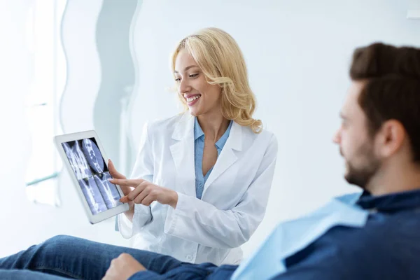 Female dentist showing man patient treatment goal, using tablet — Stockfoto