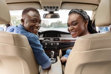 Beautiful black family sitting at front car seats and smiling