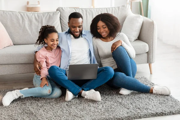 Familia negra feliz usando el ordenador portátil en la sala de estar — Foto de Stock