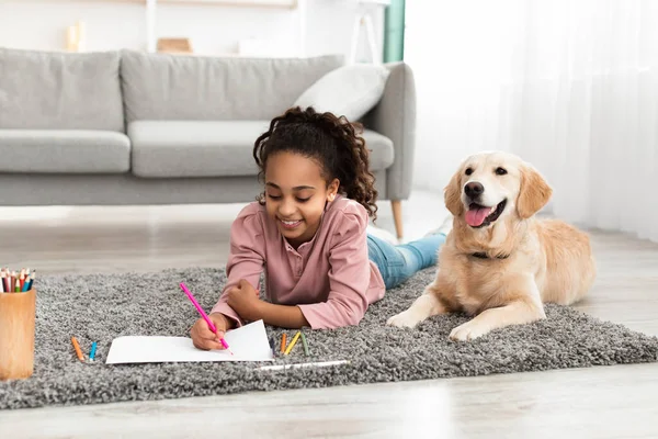 Young afro girl drawing picture with dog at home — Stock Photo, Image