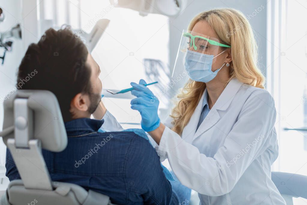 Man attendist dental clinic, sitting in chair, having checkup