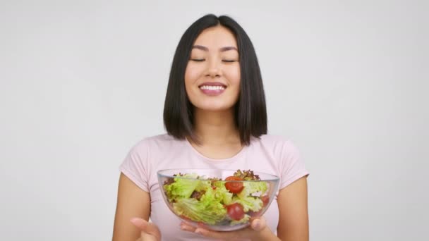 Alegre senhora japonesa segurando tigela de salada Gesturing Thumbs-Up, fundo branco — Vídeo de Stock