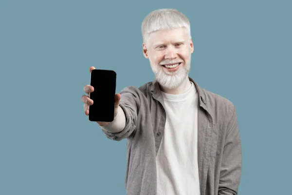 Bu uygulamayı öneririm. Gülümseyen albino adam elinde boş ekranlı akıllı telefon tutuyor, turkuaz stüdyo arka planında izole edilmiş. — Stok fotoğraf