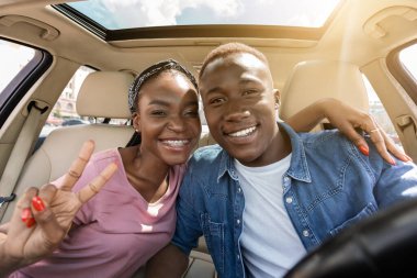 Mutlu siyahi aşıklar araba yolculuğu yaparken selfie çekiyorlar.