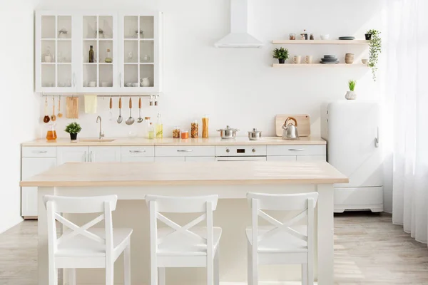 Stílus minimalizmus. Stílusos konyha fehér és barna fa. Étkezőasztal, edények és konyhai eszközök a polcokon — Stock Fotó