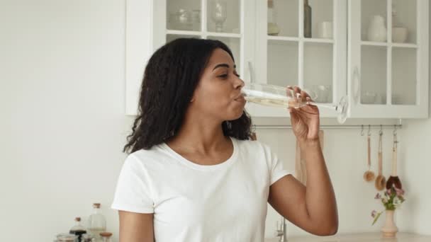 Mujer africana bebiendo vino espumoso cocinando preparando la cena en la cocina — Vídeos de Stock