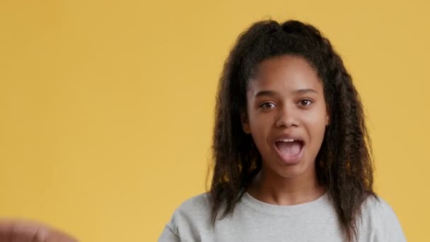 Positive african american teenage girl showing OK gesture and saying okey, orange studio background with empty space — Stock Video