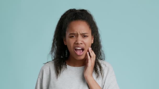 ความไวของฟัน ผู้หญิงวัยรุ่นชาวแอฟริกันอเมริกันที่เจ็บปวดฟันสัมผัสแก้มอักเสบและยิ้ม — วีดีโอสต็อก