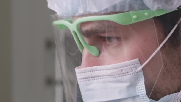 Κοντινό πορτρέτο του γιατρού οδοντίατρου φορώντας προστατευτική μάσκα προσώπου και οθόνη θεραπεία των δοντιών του ασθενούς στην κλινική — Αρχείο Βίντεο
