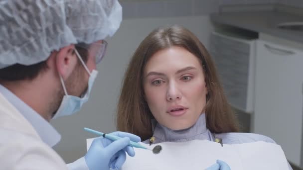 Concepto de dentofobia. Mujer joven asustada mirando al dentista con herramientas, sintiendo miedo y miedo en el consultorio dental — Vídeo de stock