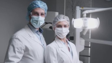 Profesyonel dişçiden ve asistanından oluşan yüksek nitelikli bir ekip klinikte dişçi ekipmanıyla poz veriyor.