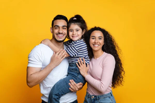 Feliz família de Páscoa média com a pequena filha abraçando e sorrindo para a câmera — Fotografia de Stock