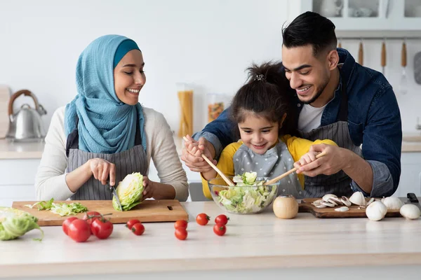 Küçük kızıyla birlikte mutfakta salata pişiren Orta Doğulu mutlu bir aile. — Stok fotoğraf