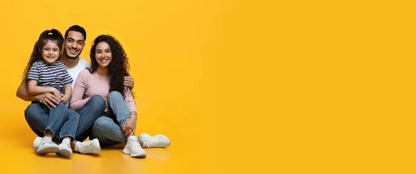 Retrato de família árabe feliz com pequena filha posando sobre fundo amarelo — Fotografia de Stock