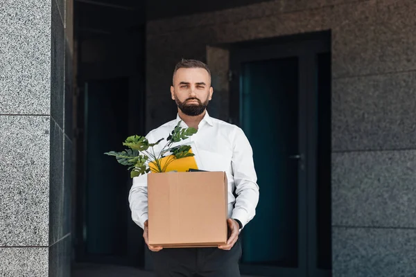 Rozrušený dospělý obchodník stojící venku s krabicí věcí. Růst míry nezaměstnanosti a koncepce snižování počtu zaměstnanců — Stock fotografie