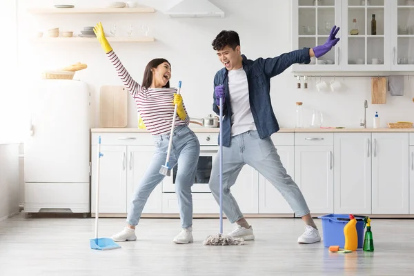 Engraçado asiático casal cantando canções enquanto limpeza de cozinha, comprimento total — Fotografia de Stock
