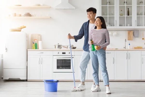 Joven asiático pareja fregando piso en cocina — Foto de Stock
