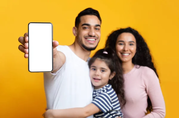 Família feliz do Oriente Médio de três mostrando tela de smartphone em branco para mockup — Fotografia de Stock