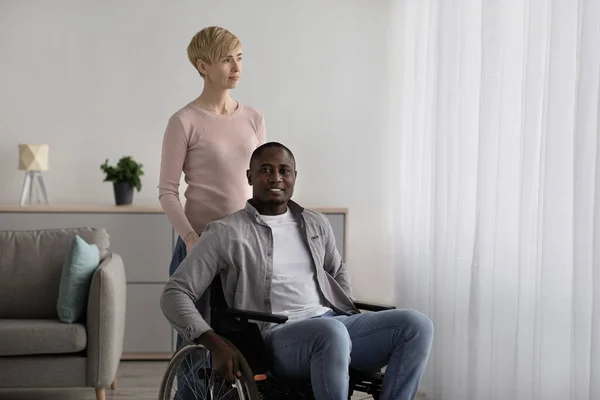 Házi ápoló gondozza a fogyatékos beteget. Multiracionális család — Stock Fotó