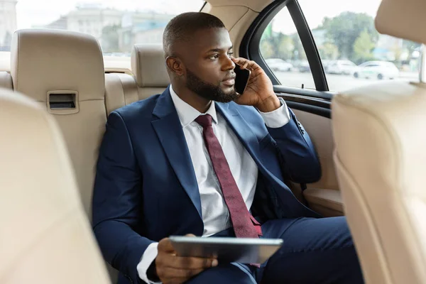 Reicher schwarzer Manager sitzt im Auto und nutzt digitales Tablet — Stockfoto
