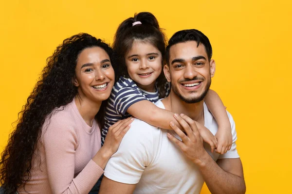 Retrato de alegre família árabe com filha abraçando e sorrindo para a câmera — Fotografia de Stock