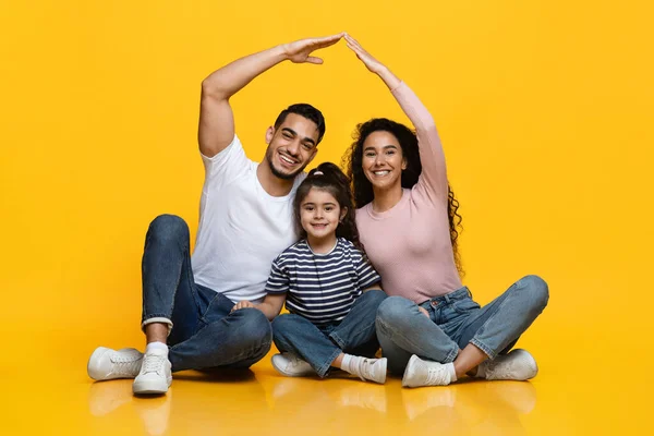 Aile Sigorta Konsepti. Mutlu Arap ebeveynler küçük şirin bir kızın üstünde çatı yapıyor. — Stok fotoğraf