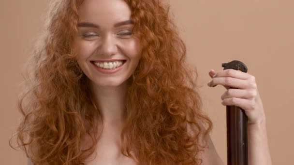 Red-Haired γυναίκα Spraying Hairspray Στυλ σγουρά μαλλιά σε μπεζ φόντο — Αρχείο Βίντεο