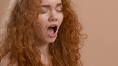 Uykucu, kızıl saçlı, esneyen, ağzı kapalı, bej arkaplan