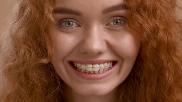 Dama con tirantes sonriendo chasquear los dientes posando sobre fondo beige — Vídeo de stock