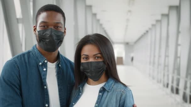 Μαύροι τουρίστες ζευγάρι φορώντας προστατευτικές μάσκες προσώπου στέκεται στο αεροδρόμιο — Αρχείο Βίντεο