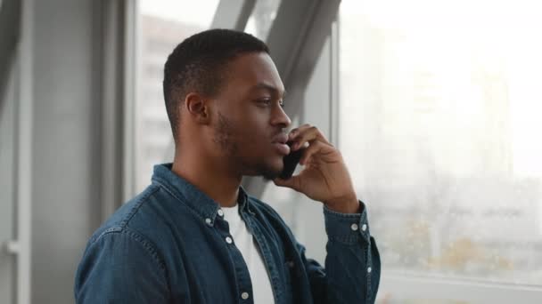Афроамериканський мандрівник, який розмовляє по телефону, стоїть в аеропорту — стокове відео