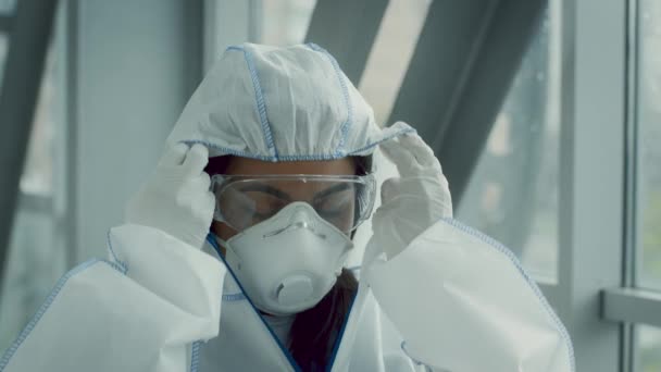 Vrouwelijke medische werknemer neemt Hazmat pak en masker Indoor — Stockvideo