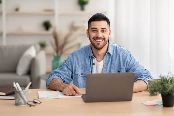 Souriant homme israélien travaillant sur ordinateur portable à la maison — Photo