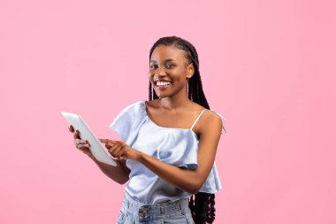 Tabletli genç siyahi kadın aile veya arkadaşlarıyla sohbet ediyor, pembe arka plan üzerine iş konferansı yapıyor.