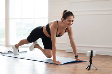 Akıllı telefonun önünde bacak esneten genç bir kadın.