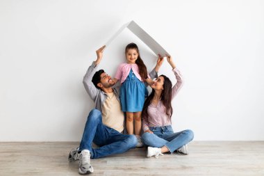 Genç aile kavramı için konut. Doğu 'lu genç baba, anne ve kız sembolik çatı altında.