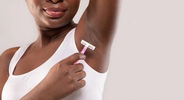 Närbild av oigenkännlig afroamerikansk dam rakning underarm med rosa rakkniv — Stockfoto