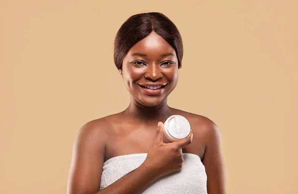 Hidratante de pele. bela jovem preto senhora segurando jarro com nutritivo creme e sorrindo para câmara — Fotografia de Stock
