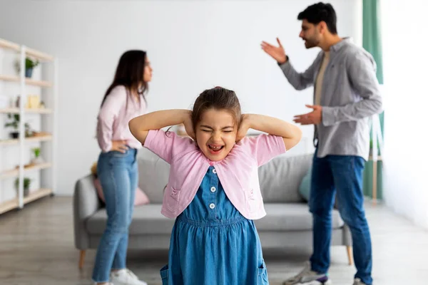 Familjegräl. Gråter liten östlig flicka täcker öronen inte höra föräldrar gräl, selektiv fokus — Stockfoto