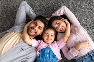 Bağlanma konsepti. Üç kişilik doğu manzaralı bir portre. Evde, halının üzerinde birlikte yatıyorlar.