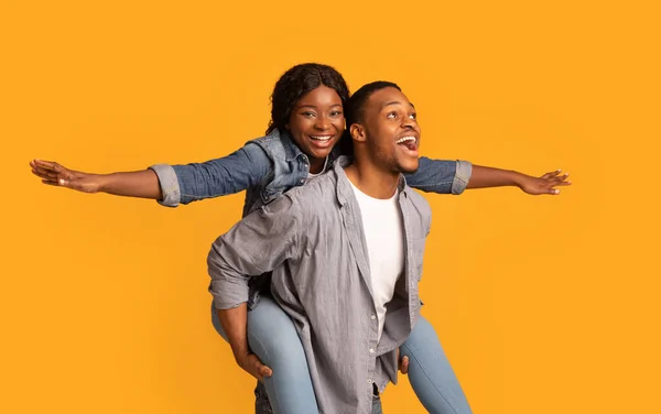 Joyful Black Couple Having Fun Together Over Yellow Background, Woman Piggybacking Boyfriend — 图库照片