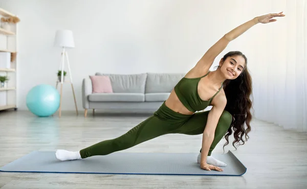Giovane donna indiana praticare yoga o pilates, stretching braccia e gambe durante l'allenamento domestico, spazio copia — Foto Stock